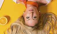 Portrait of Blonde Girl Lying on Yellow Background with Oranges Presentation Template